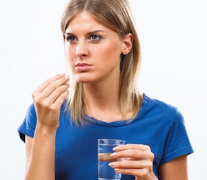Woman Holding Glass of Water and Pill